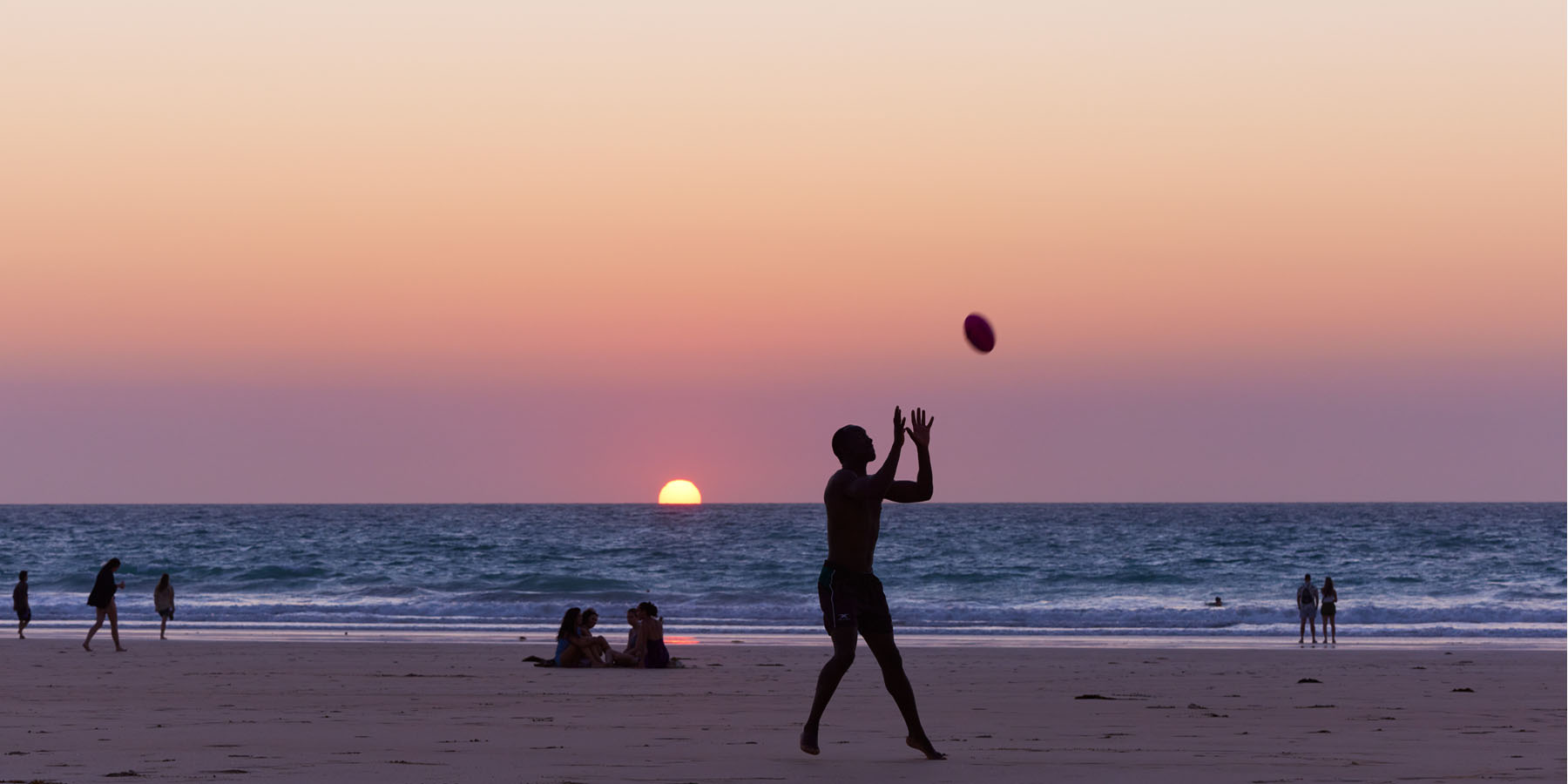 Image of people playing football on the beach near Pinctada Hotel
